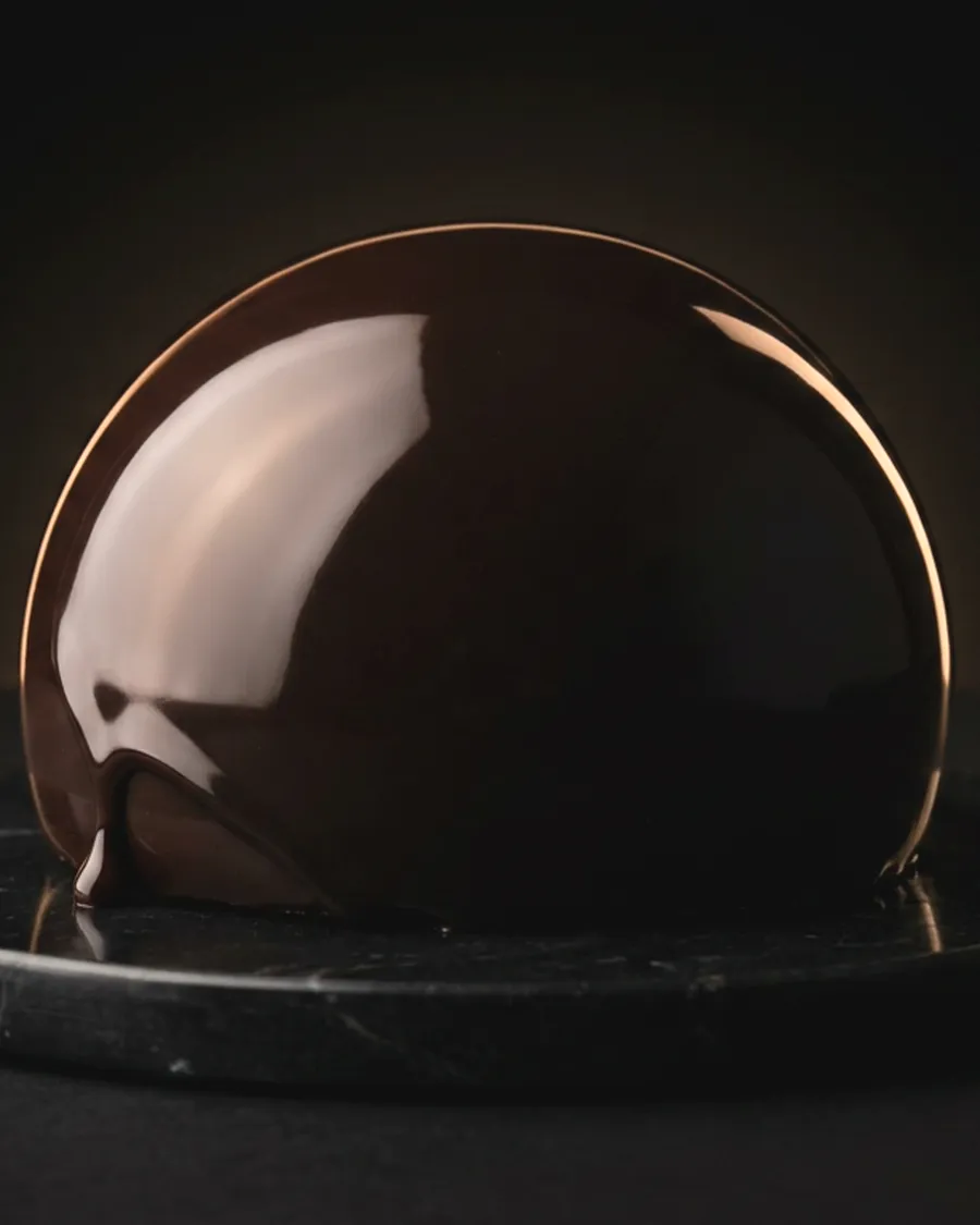 A mirror-glazed dark chocolate dome crowned with gold leaf