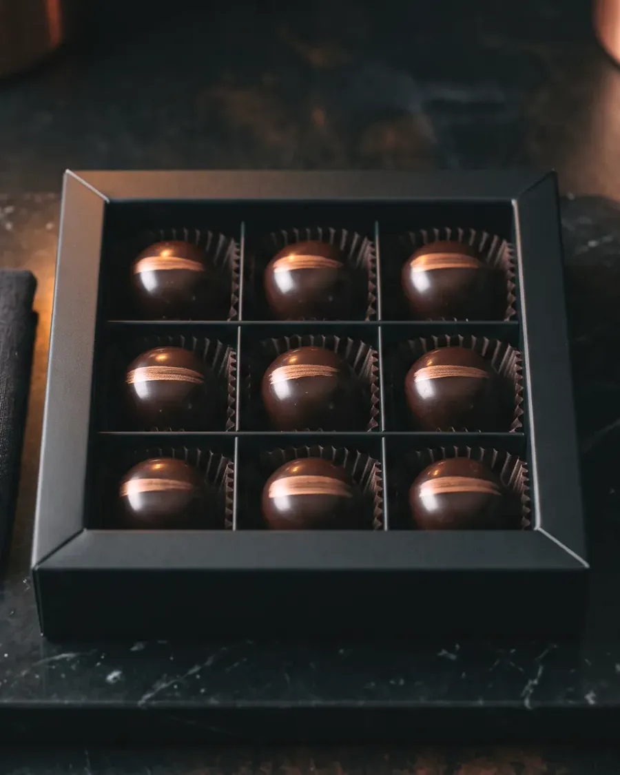 Nine polished dark chocolate bonbons in a black box